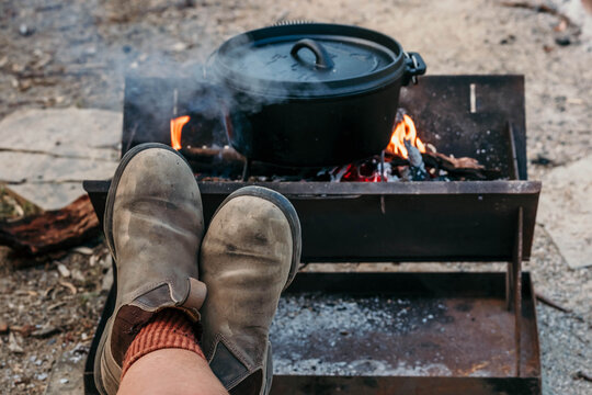 Camp fire cooking with boots up resting.