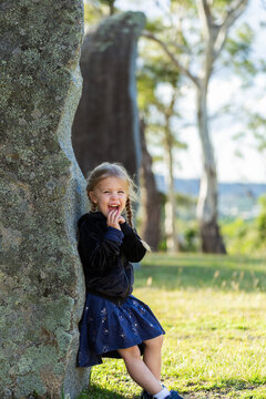laughing child leaning on Iconic Australian standing stones enjoying the Glen Innes Highlands