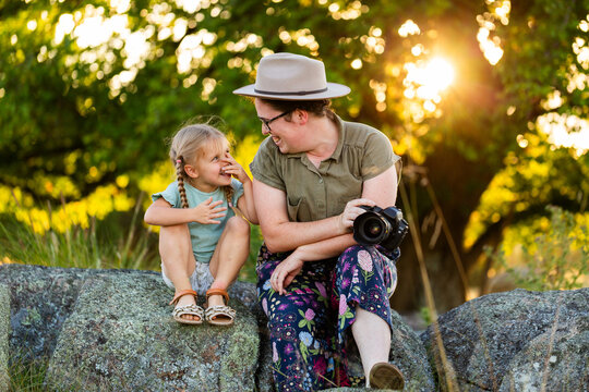 Photographer mum sitting with young kid on rock outdoors at photoshoot location