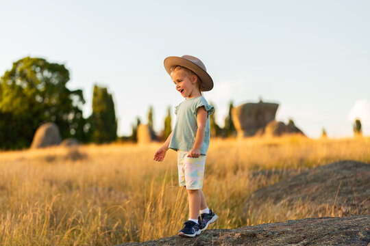 Australian child playing on rocks in grassy paddock at sunset enjoying the summer evening