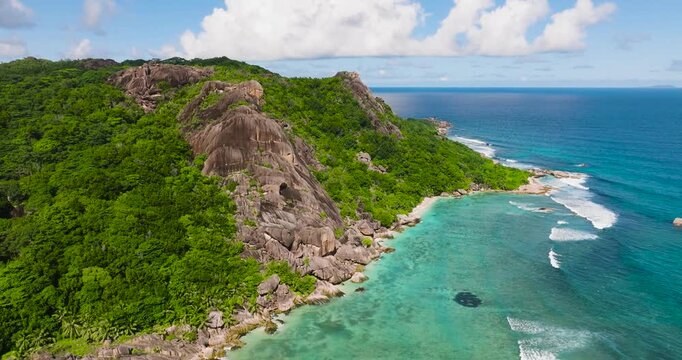 Granite cliffs rise above turquoise waters on a tropical coastline. Seychelles, La Digue.