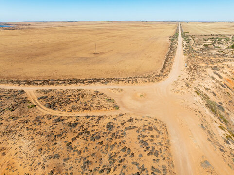 Aerial view of erosion and a long straight road though an arid landscape