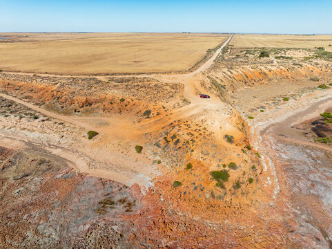 Aerial view of a 4WD parked on a remote arid headland above a rocky coastline