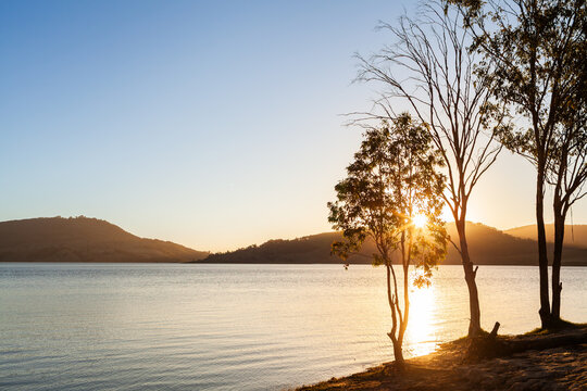 Golden sun setting over hills across lake in Hunter Valley