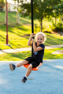 Happy little girl playing outdoors swinging on flying fox zipline at park playground