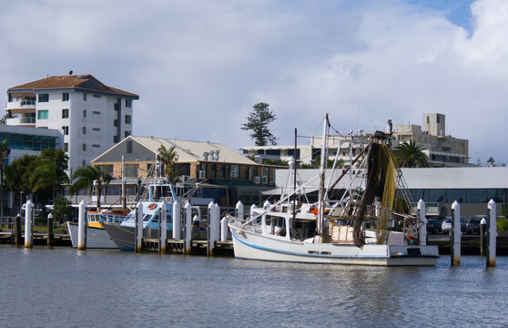 Fishing boats moored in river with waterfront buildings on shoreline