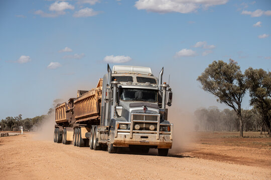 Truck pulling side tippers of gravel along a dirt road