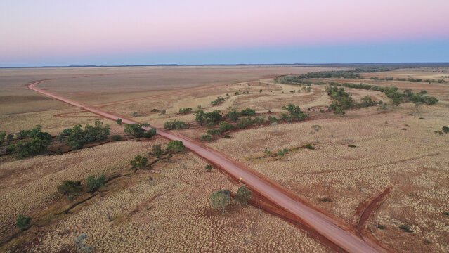 Drone shot of a dirt road going through creek and plain