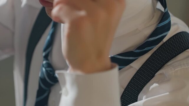 Young asian man adjusting striped tie, finetuning knot and collar, rehearsal for pitch and audition scenes, salesman checking posture, actor rehearsing entrance, moody cinematic closeups of hands