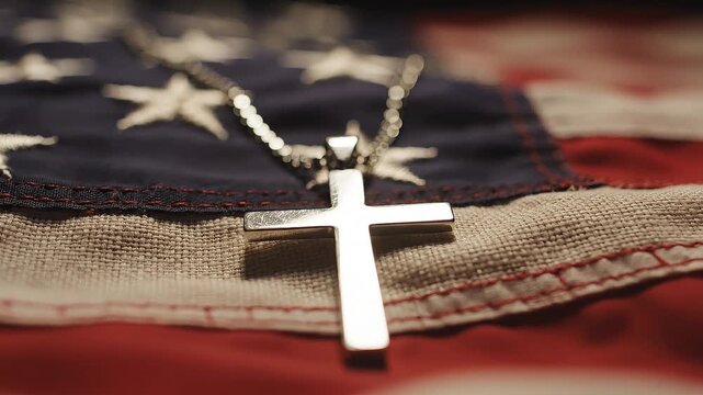 A silver cross pendant rests on a textured American flag, representating Memorial Day, Veterans Day, or other patriotic USA holiday.
