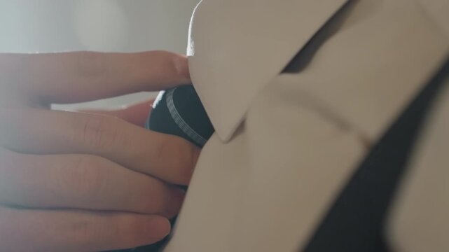 Soft light closeup hand adjusting tie, textured navy tie with subtle pattern and crisp collar, suspenders visible in warm backlight poised groom or executive completing final touch in elegant morning