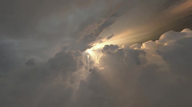High Speed FPV Weaving Through Ominous Dark Gray Storm Clouds With Majestic Golden Sunrays Shining