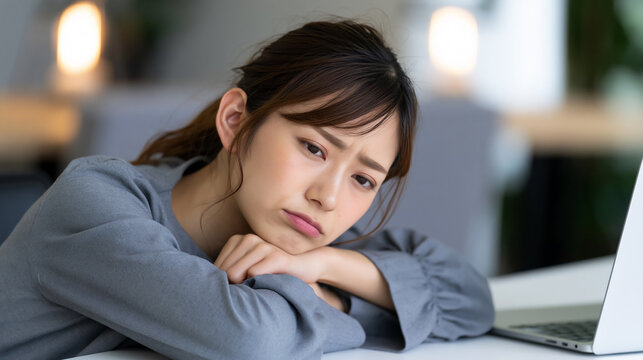 Depressed and bored young woman leaning on her arms at an office desk