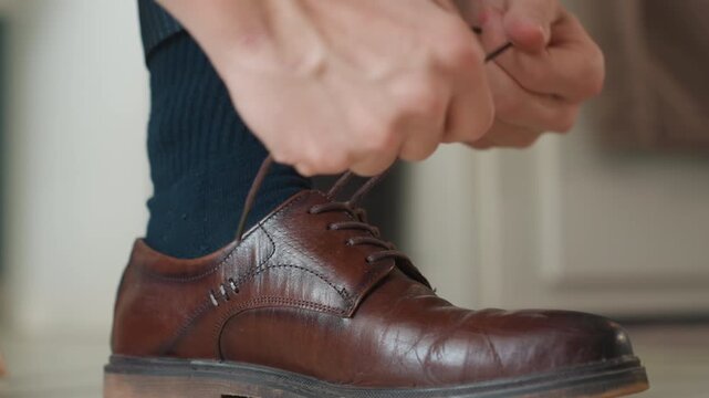 Close up brown leather shoe tightened quickly man hurries to office, brisk fingers loop lace, scuffed sole, indoor hallway, suit trousers hint, punctual mood, urban morning energy