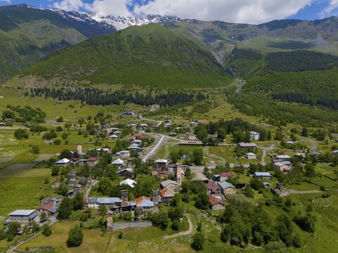 Idyllic village landscape embedded in the mountainous region with many buildings and green fields, aerial view, Majvdieri, Mestia municipality, Svaneti, Caucasus, Georgia
