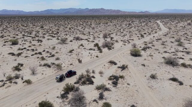 An SUV tows a teardrop camper trailer through the open desert landscape near El Salar salt flats in Baja California.