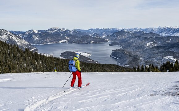 Skiers skiing down the Simetsberg, view of Walchensee and mountain panorama, Estergebirge, Bavarian Prealps, Bavaria Germany