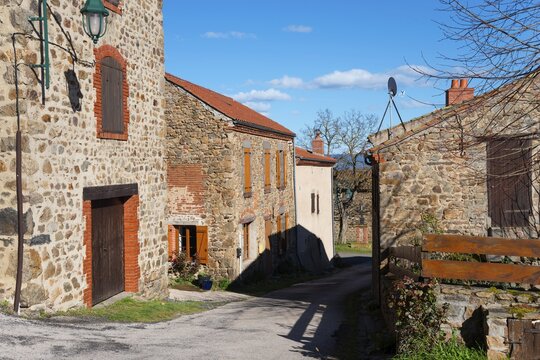 Eine ruhige Dorfstra&szlig;e mit steinernen H&auml;usern und Fensterl&auml;den unter einem sonnigen, blauen Himmel, L&eacute;otoing, Leotoing, Haute-Loire, Auvergne-Rh&ocirc;ne-Alpes, Auvergne-Rhone-Alpes, Frankreich