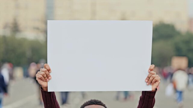 Person holding blank protest sign in city, freedom of speech and activism concept.