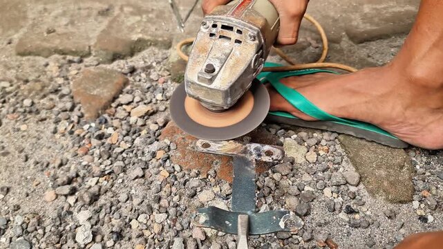 Sidoarjo, Indonesia - 30 May, 2026: Maker modifying metal parts using an angle grinder and pliers outdoors
