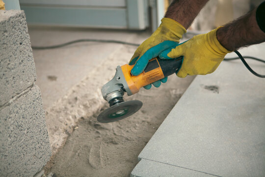 Close-up of worker polishing concrete slab with electric grinder