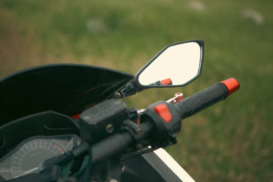 Motorcycle rear view mirror on green grass background. Close up.