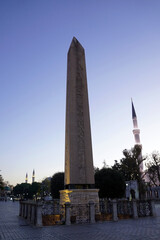 Obraz premium The ancient Egyptian Obelisk of Theodosius stands prominently in the Hippodrome of Constantinople with the slender minarets of the Blue Mosque visible in the background under a clear twilight sky
