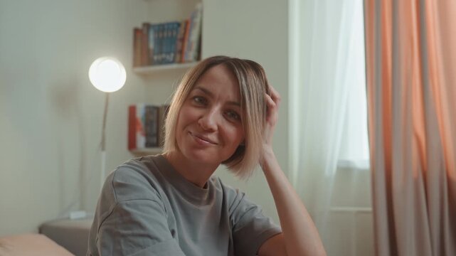 Woman with braids enjoying music, sunlit curtain backdrop and lamp glow, candid smiles and flirtatious gestures, casual tee, upbeat lofi ambiance, confident charm, playful selfcare moment, amateur