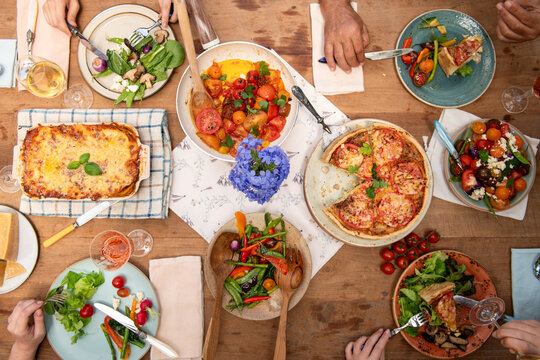 Aerial view of a diverse group enjoying a colorful meal at a wooden table.