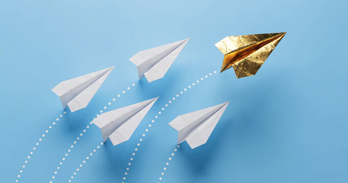 Unique leadership concept with shiny gold paper aircraft paving a new path on blue backdrop. Think differently and business innovation concept with a gold plane leading white airplanes