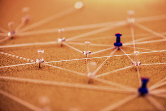 Close-up of pushpins and string connected across a cork board