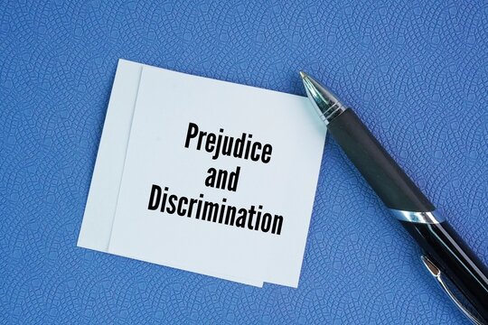 Pen and paper with the words Prejudice and Discrimination. prejudice is an attitude or feeling, while discrimination is an action or behavior