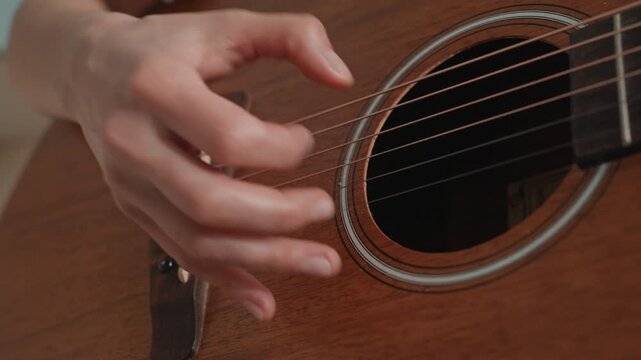 Closeup hands fingerpicking acoustic guitar, warm wood body, soft natural light, slow expressive tempo, right hand technique focus, gentle nails, home practice session, cozy studio atmosphere, tender