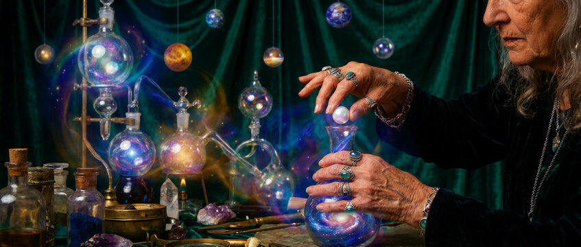 Witch alchemist mixing cosmic potion in mystical lab. Hands with rings hold glass vessel filled with a swirling galaxy. Fantasy alchemy concept ideal for occult and spiritual storytelling.