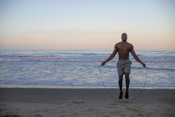 Naklejka premium Man jumping rope on beach
