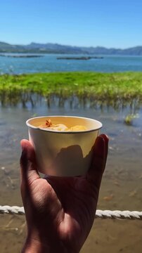 Hand holding a cup of fried bananas with beautiful landscape background. 4K vertical footage format