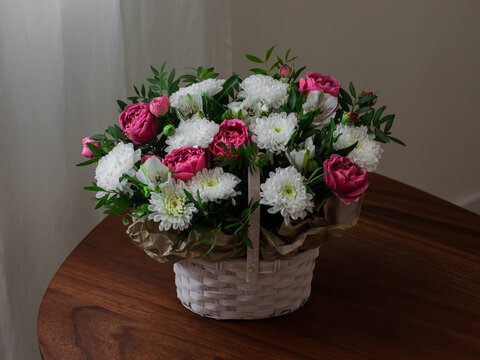 Bouquet of peony-shaped roses, chrysanthemums, astromellias in a basket on a wooden table