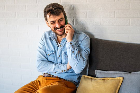 Man smiling during a phone call indoors captures a lively social moment full of friendly connection