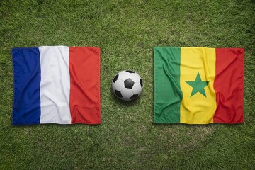 Naklejka premium France and Senegal national flags displayed on a vibrant green grass field with a soccer ball