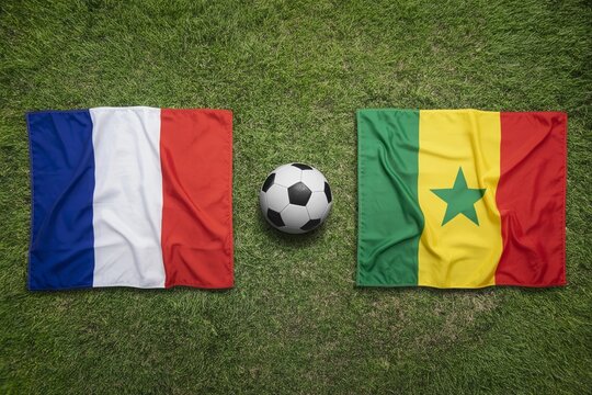 France and Senegal national flags displayed on a vibrant green grass field with a soccer ball