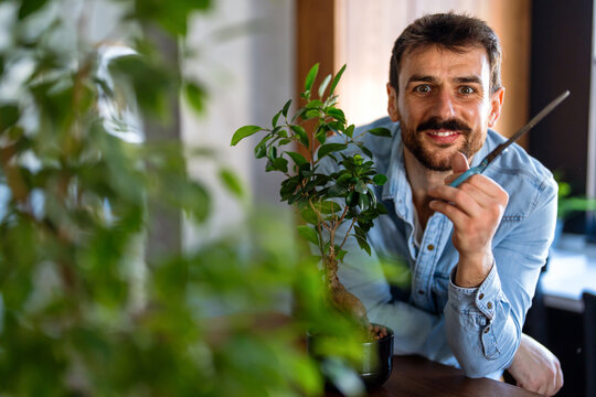 Man caring for his indoor plants in home, embracing the beauty of nature in everyday urban life