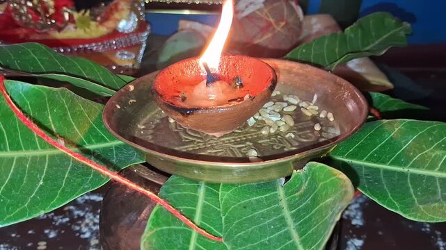Traditional Hindu Puja Setup with Burning Clay Diya and Mango Leaves
