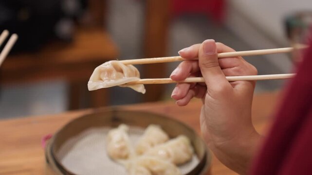 Steamed dumpling scene. Warm ambiance as chef handles freshly steamed dumplings on wooden table. Cozy kitchen setting with chef selecting steamed buns from bamboo steamer under dim lighting