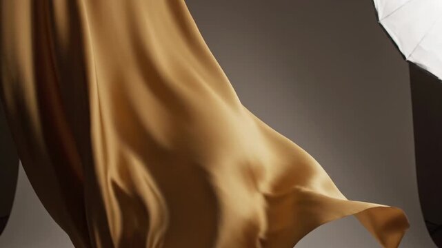 flowing golden silk fabric, draped elegantly with soft folds and highlights, studio lighting on a subtle gradient background