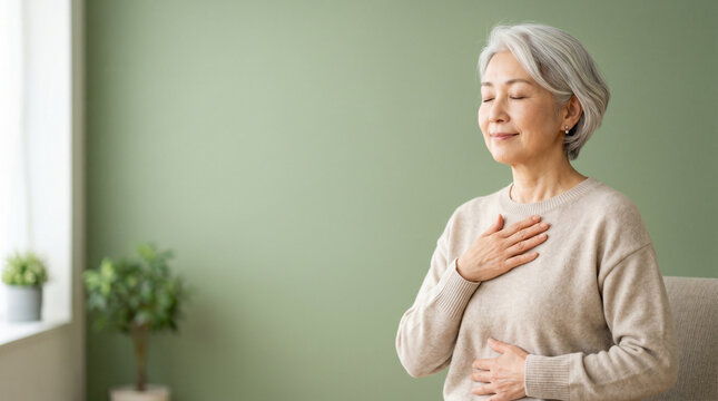 穏やかな時間を楽しむ70代日本人女性のウェルネスイメージ。
淡いグリーン背景と自然光が健康的で安心感のある雰囲気を演出。
健康寿命やアクティブシニア、長寿社会のテーマに最適。