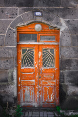 Obraz premium Old rustic door set in stone archway, faded orange with decorative glass