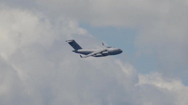 C-17 Globemaster performs strategic airlift maneuvers during training operations in a cloudy sky