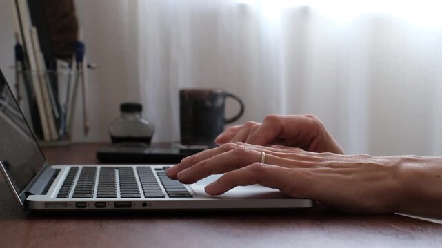 Close-up of hand using laptop trackpad at home office desk 在宅ワーク環境でノートパソコンのトラックパッドを操作する手元のクローズアップ