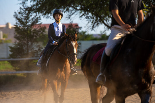 Young girl horseback riding in a dusty arena