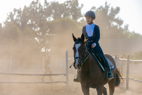 Young girl in equestrian gear rides her horse